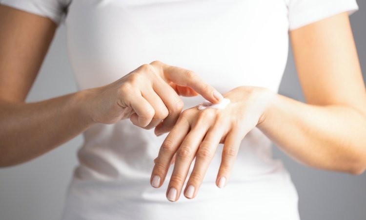 Nahaufnahme einer Frau, die sich eine Creme auf ihren Handrücken aufträgt